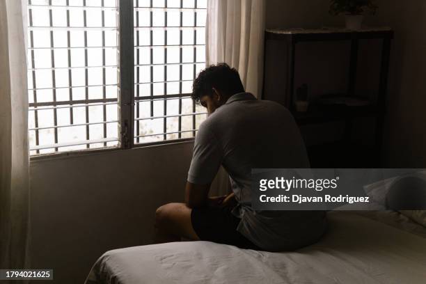 alone man sitting on the bed. masculinity and emasculation concept. - emasculation stock pictures, royalty-free photos & images