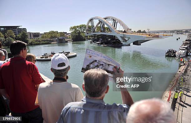 People observe as the new Raymond Barre bridge is placed outside the new Confluences Museum in Lyon, southeastern France, on September 3, 2013. AFP...