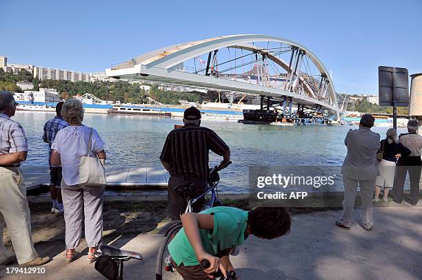 People observe as the new Raymond Barre bridge is placed outside the new Confluences Museum in Lyon, southeastern France, on September 3, 2013. AFP...