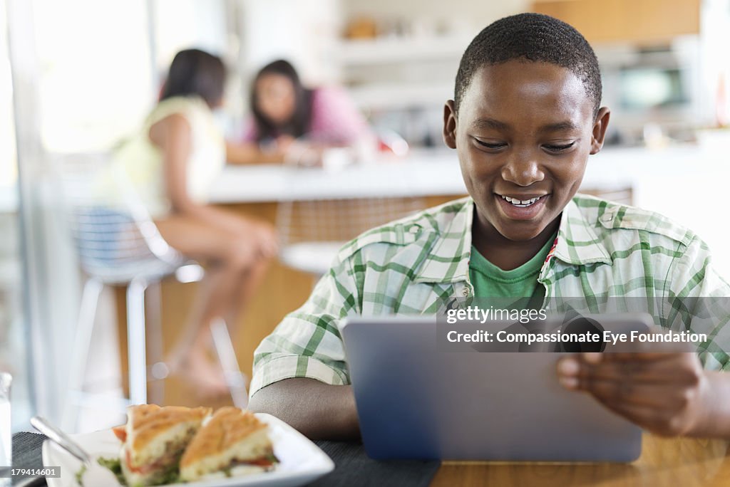 Smiling boy using digital tablet in kitchen