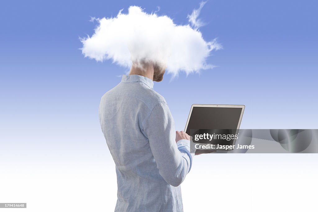 Man using laptop with his head in the clouds