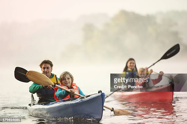family paddling in a canoe on a lake - andare in canoa foto e immagini stock