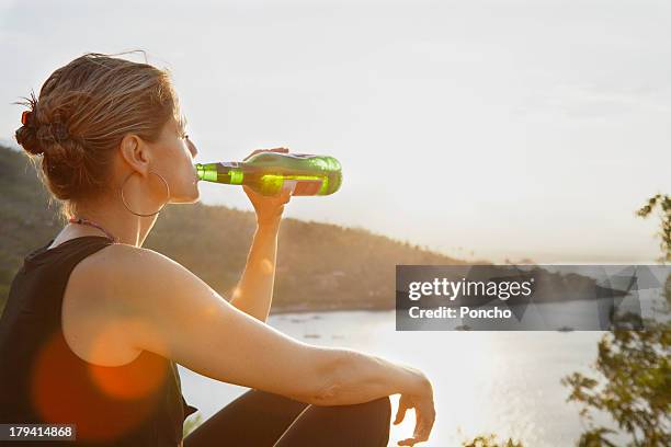 woman enjoying a beer in the sunset up a bay - bier trinken stock-fotos und bilder