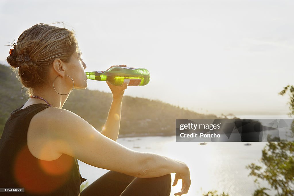 Woman enjoying a beer in the sunset up a bay