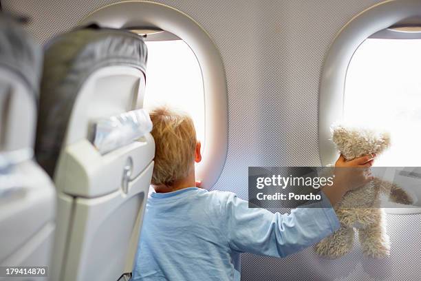 boy sitting in an airplane holding a teddy - kind teddy sitzt stock-fotos und bilder