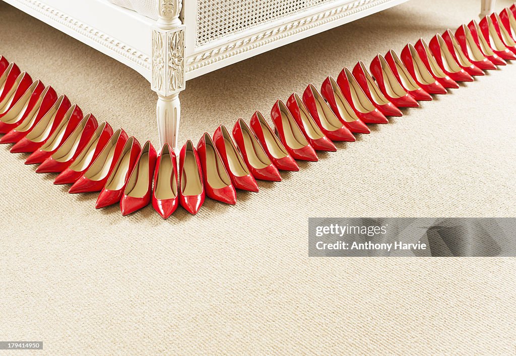 Red shoes in a row next to bed