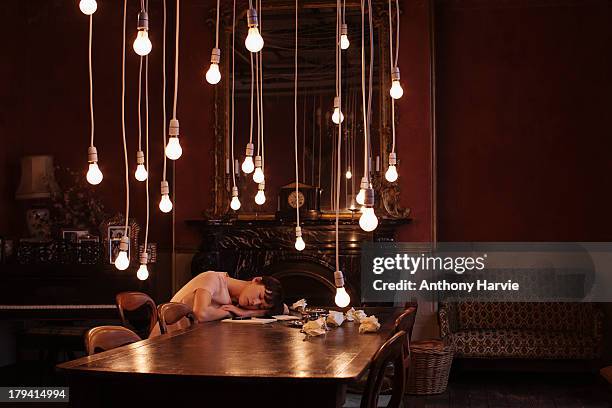 woman asleep at table with hanging lightbulbs - woman sleeping table stock pictures, royalty-free photos & images