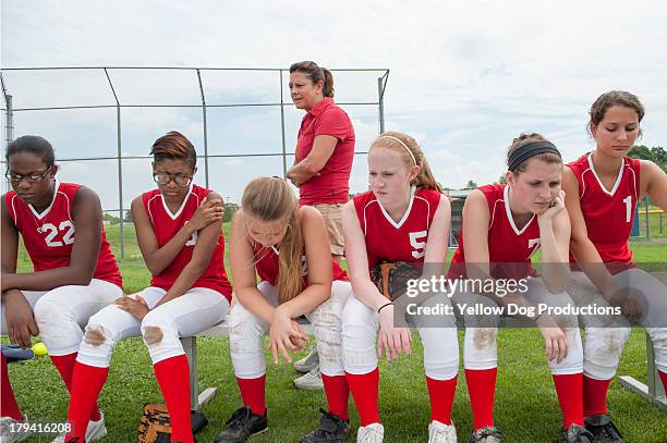 coach with players sitting with heads down - softball sport stock-fotos und bilder