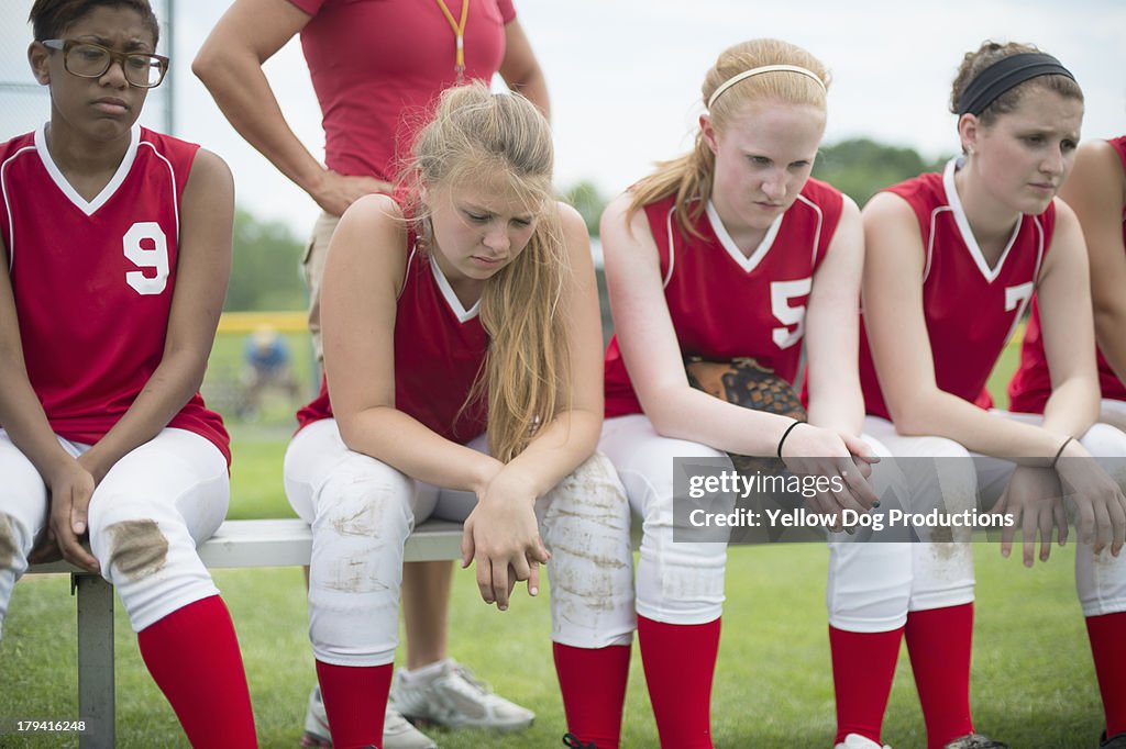 Softball Players Sitting with Heads down on Bench