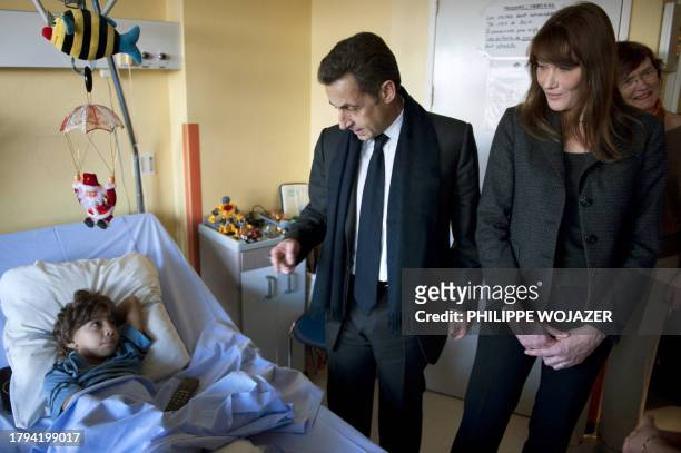 France's president Nicolas Sarkozy and his wife Carla Bruni-Sarkozy speak with a child at the Saint-Denis children hospital eyed by Elisabeth Beau,...