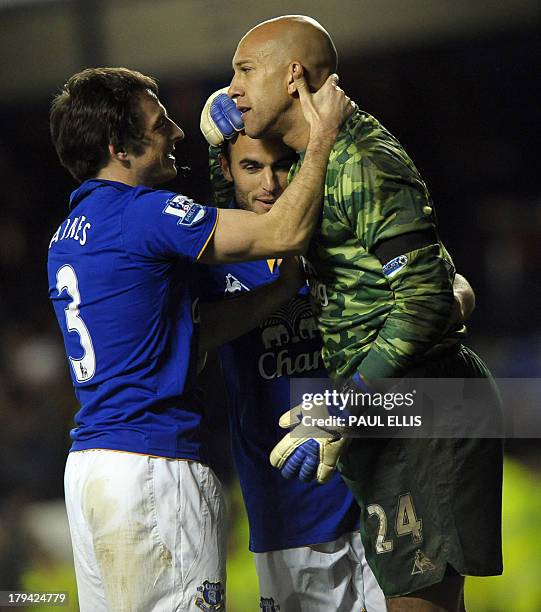 Everton's English defender Leighton Baines and Everton's US forward Landon Donovan congratulate Everton's American goalkeeper Tim Howard after the...