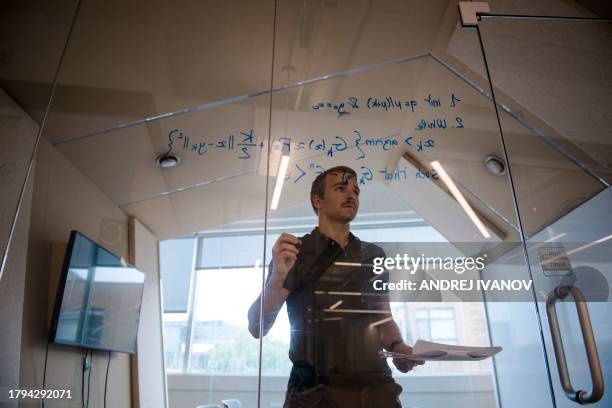 Basile Roth, an employee at Mila Quebec AI Institute poses for a scene for the videographer writing lines of code on a glass panel on July 4 in...
