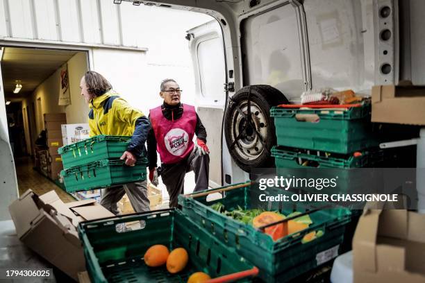 Volunteers of French charity "Les Restos Du Coeur" carry food on November 21, 2023 at a facility of the association in Grenoble, during the launch of...