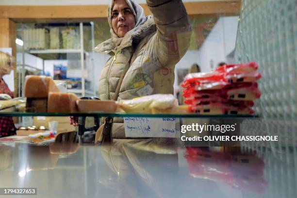 Woman receives food at a facility of French charity "Les Restos Du Coeur" on November 21, 2023 at a facility of the association in Grenoble, during...