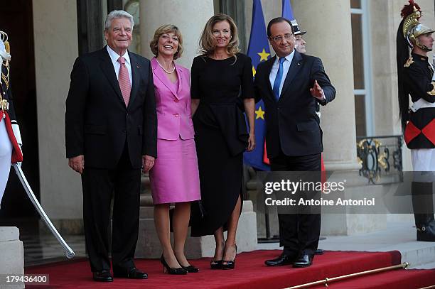 French President Francois Hollande and his companion Valerie Trierweiler pose with the German President's companion Daniela Schadt and the German...