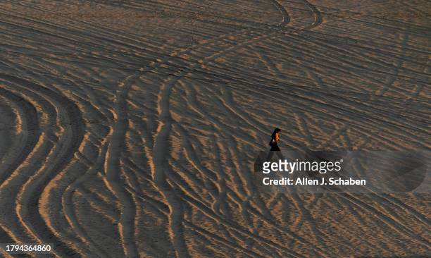 Santa Monica, CA A beach comber takes a sunset stroll across converging patterns in the sand amidst pleasant weather in Santa Monica Monday, Nov. 20,...