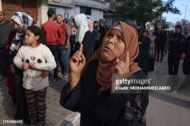 Woman gestures as Palestinians wait to buy bread in Khan Yunis in the southern Gaza Strip on November 21 amid the ongoing battles between Israel and...