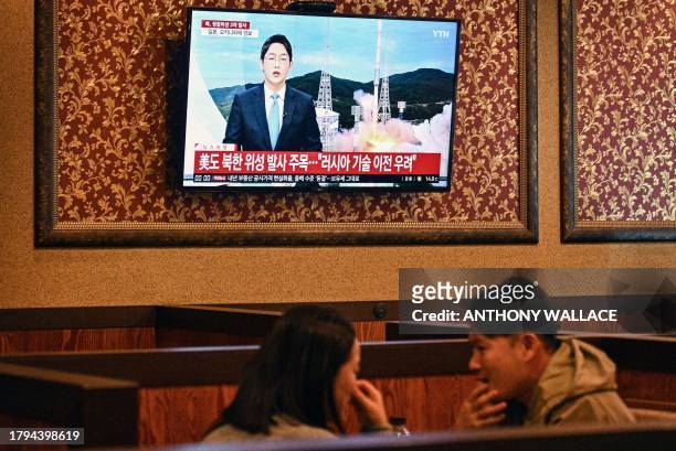 Customers sit near a television showing a news broadcast at a restaurant in Seoul on November 21 after North Korea fired what it claims is a military...