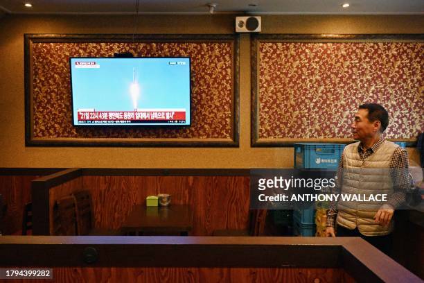 Man watches a television showing a news broadcast at a restaurant in Seoul late on November 21 after North Korea fired what it claims is a military...