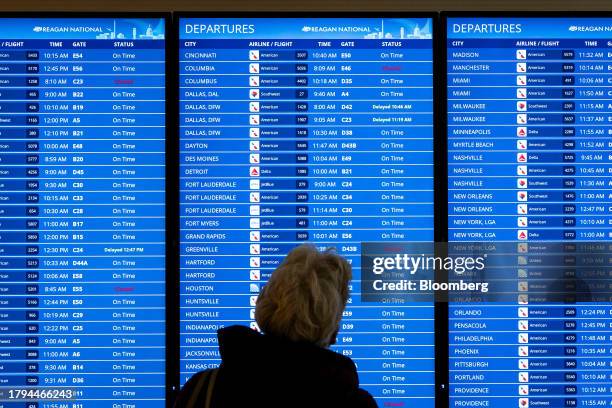 Traveler checks departures boards at Ronald Reagan National Airport in Arlington, Virginia, U.S., on Tuesday, Nov. 21, 2023. This holiday season...