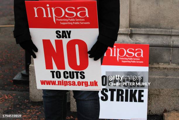 Worker holds a banner during a public service protest over pensions outside the gates of the Stormont Parliament building in Belfast, Northern...