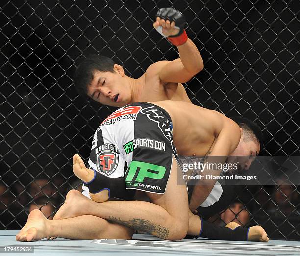 Takeya Mizugaki and Erik Perez wrestle on the cage during a bantamweight bout during UFC Fight Night 27 Condit v Kampmann 2 at Bankers Life Field...