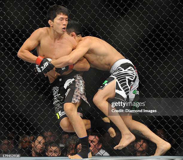 Takeya Mizugaki and Erik Perez wrestle on the cage during a bantamweight bout during UFC Fight Night 27 Condit v Kampmann 2 at Bankers Life Field...