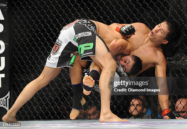 Takeya Mizugaki and Erik Perez wrestle on the cage during a bantamweight bout during UFC Fight Night 27 Condit v Kampmann 2 at Bankers Life Field...