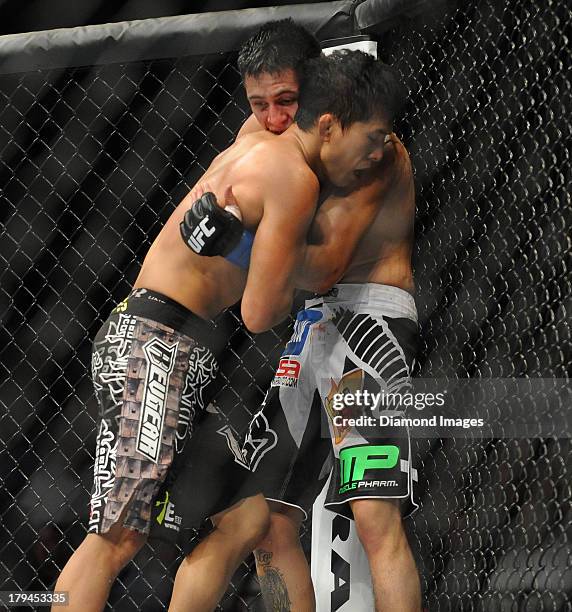 Takeya Mizugaki and Erik Perez wrestle on the cage during a bantamweight bout during UFC Fight Night 27 Condit v Kampmann 2 at Bankers Life Field...