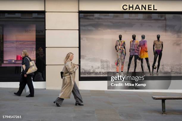 Figures of people interact with mannequins in the Chanel store window on Bond Street on 15th November 2023 in London, United Kingdom. Bond Street is...