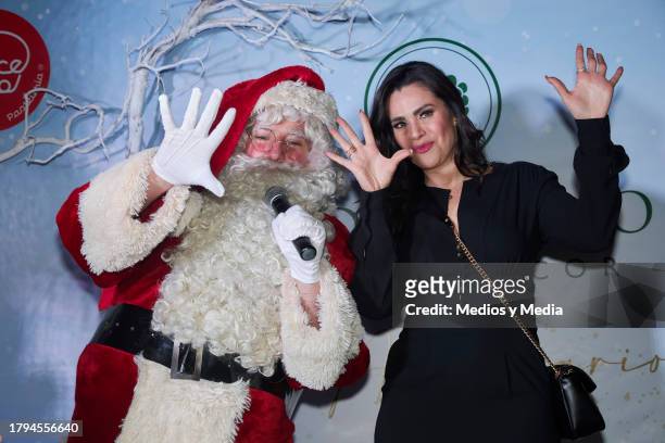 Santa Claus and Luz Elena Gonzalez pose for a photo during the Cristmas tree lighting event by Verde Hoja Home and Decor on November 14, 2023 in...
