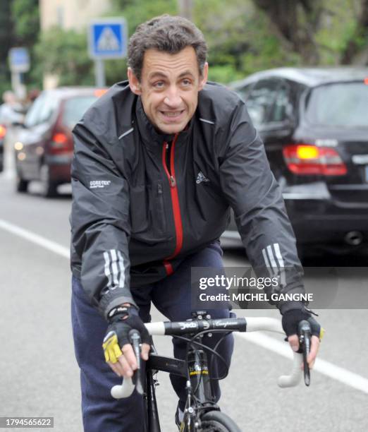 French president Nicolas Sarkozy leaves on his bike his wife, Carla Bruni-Sarkozy's residency on April 12, 2009 in the French city of Cavaliere,...