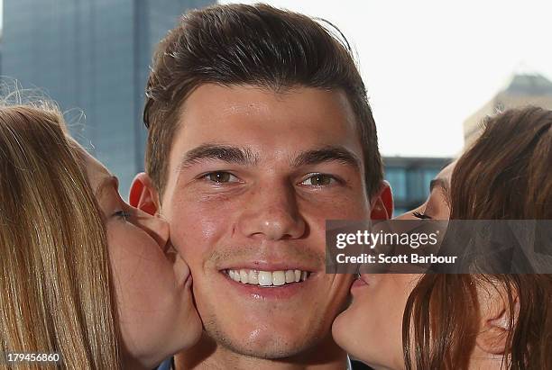 Jaeger O'Meara of the Gold Coast Suns is kissed by his sisters Jahni and Shaeli after winning the 2013 Ron Evans Medal NAB Rising Star Award as the...