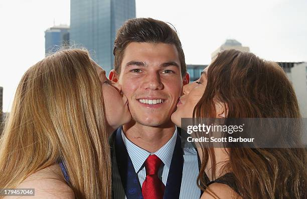 Jaeger O'Meara of the Gold Coast Suns is kissed by his sisters Jahni and Shaeli after winning the 2013 Ron Evans Medal NAB Rising Star Award as the...