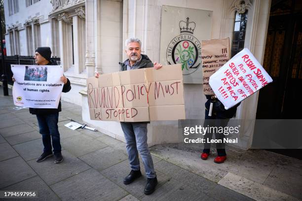 Protestors hold placards as they wait for the verdict on whether the UK Government can send refugee migrants to Rwanda, as they gather outside The...