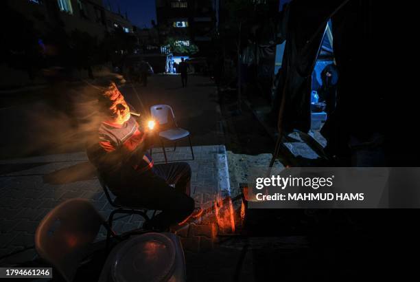 An internally displaced Palestinian man who fled the northern Gaza Strip smokes outside a makeshift shelter at a school where he and others are...