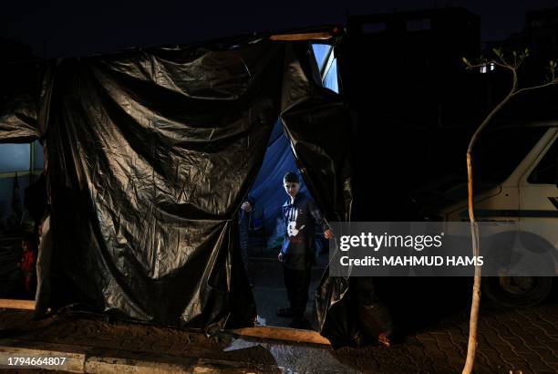 An internally displaced Palestinian boy who fled the northern Gaza Strip stands at the entrance of a makeshift shelter at a school where he and...