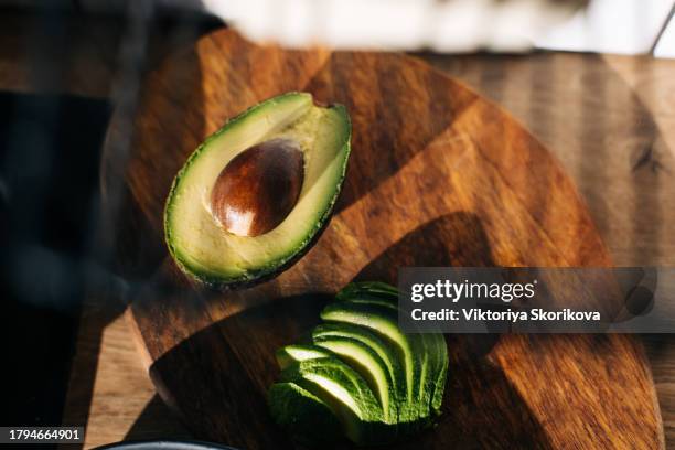 avocado cut open on a chopping board - avocado stock-fotos und bilder