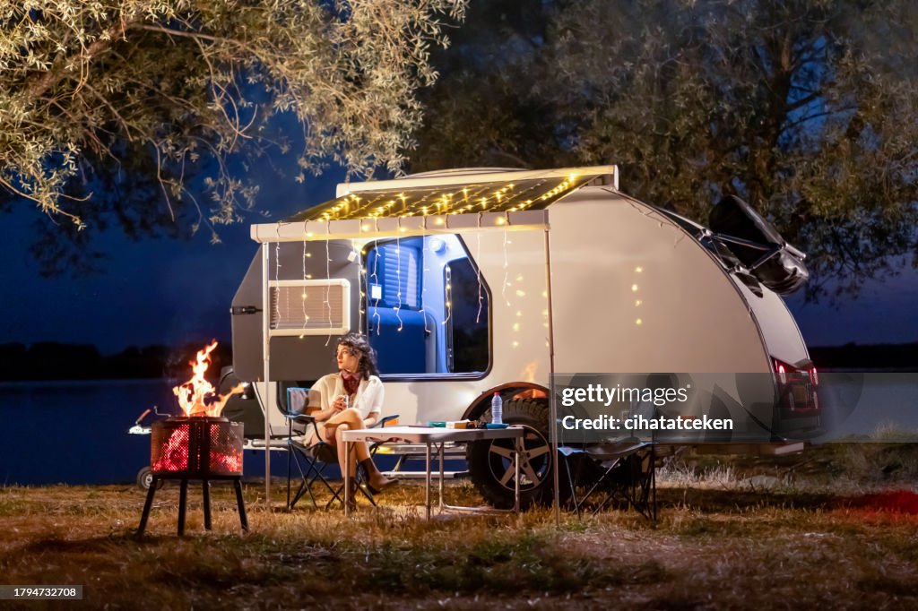 Travel trailer and woman camping at night