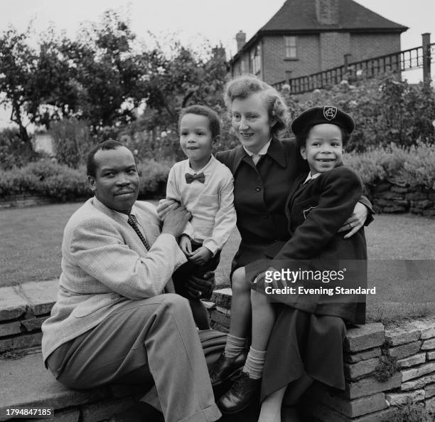 Bechuanaland Protectorate politician Seretse Khama sits beside son Ian Khama, wife Ruth Williams Khama , and daughter Jacqueline in a garden,...