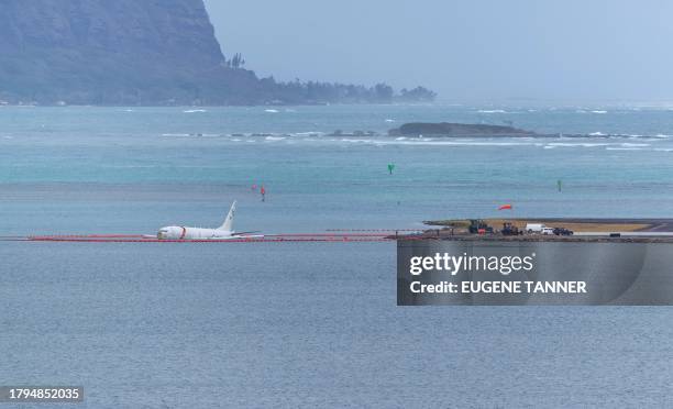Military aircraft lies in the shallow waters of Kaneohe Bay after skidding off the end of the runway at Marine Corps Hawaii in Kaneohe on November...