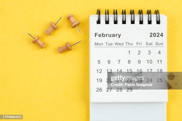 desk calendar 2024: february calendar is used to plan daily work and life with a push pin on a yellow paper background. - february stock pictures, royalty-free photos & images