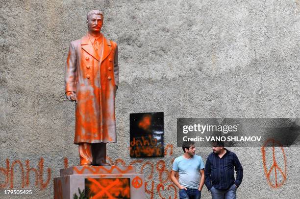 Two men speak as they stand next to a statue of Soviet leader Joseph Stalin daubed with paint in the Georgian in the town of Telavi, some 100...