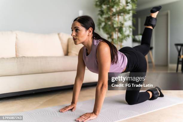 mujer joven haciendo ejercicio en la sala de estar de su casa - tobillo fotografías e imágenes de stock