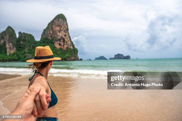 young woman holding photographer's hand on idyllic beach in thailand - andamanensee stock-fotos und bilder