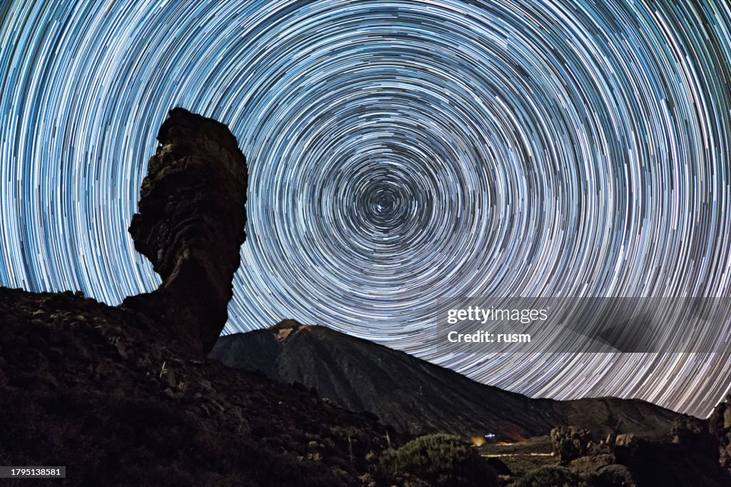 Star trails over of Teide volcano and Los Roques de Garcia rocks, Teide National Park, Tenerife, Canary islands, Spain.