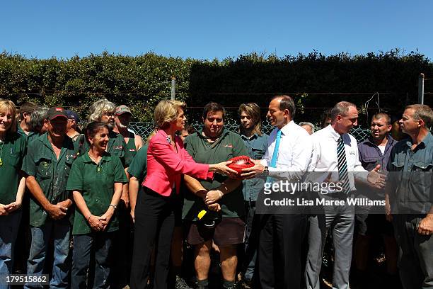 Australian Opposition Leader, Tony Abbott and Julie Bishop hold a football as they pose with staff at Packer Leather on September 5, 2013 in...