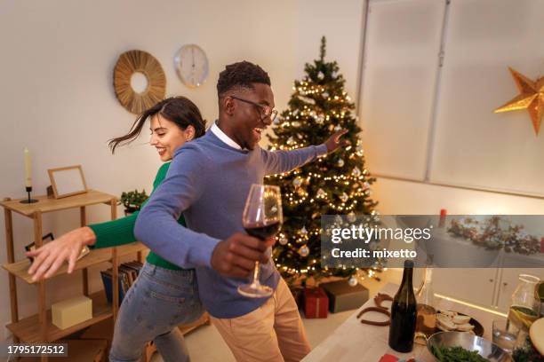 cheerful young couple dancing during christmas eve at home - couple dancing stock pictures, royalty-free photos & images