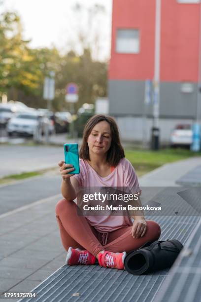 woman with birthmark sitting outdoors and holding smartphone. - modern zagreb stock pictures, royalty-free photos & images