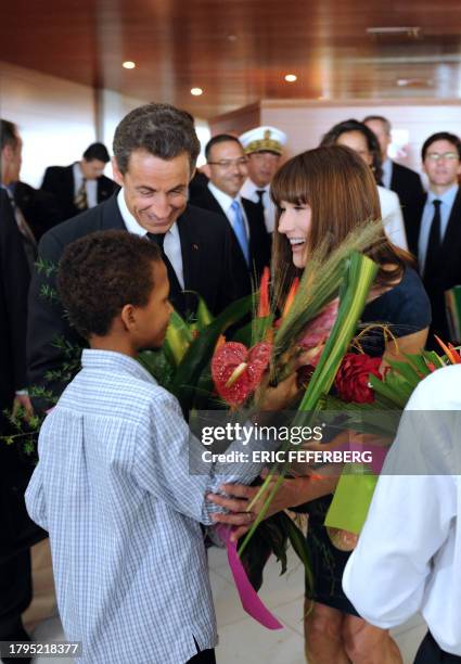 French President Nicolas Sarkozy and his wife Carla upon his arrival receive flowers from a boy at Lamentin airport on January 7 2011 in...